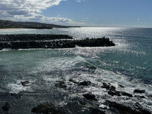 Ocean waves flowing gently through a narrow rock channel at high tide, symbolising the quiet opening that leads to spiritual harmony and inner peace.